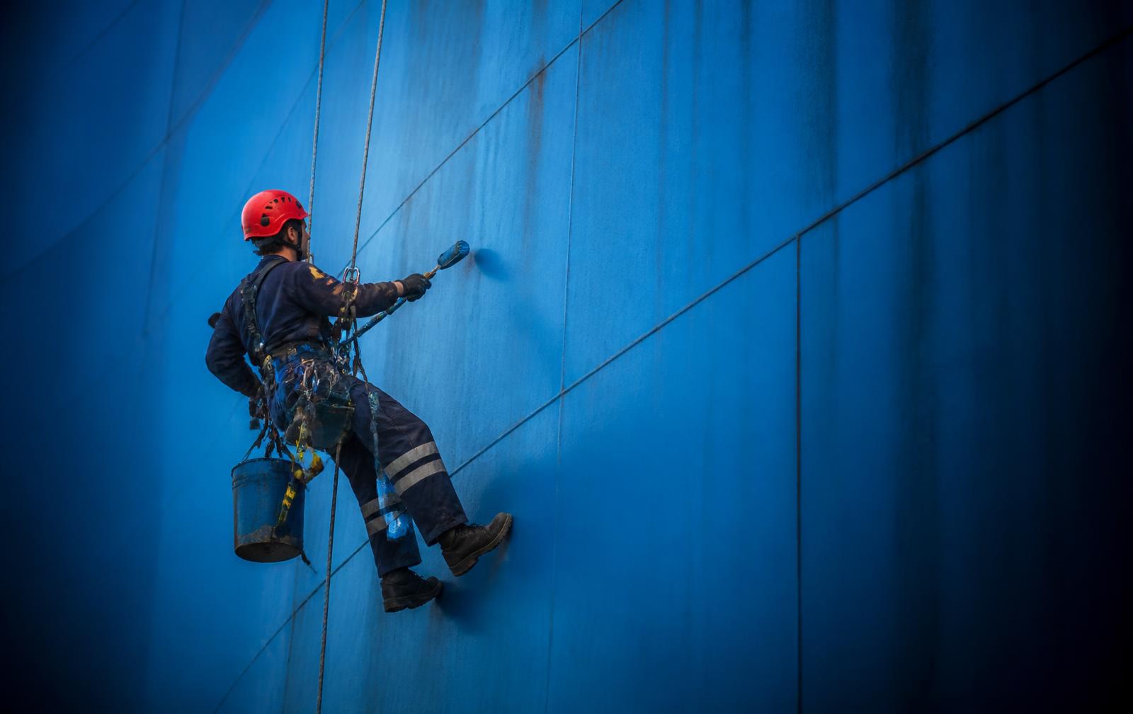 Profissional da Vertical Premium suspenso por cordas fazendo limpeza em altura